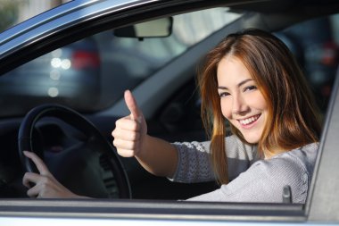 Happy woman inside a car gesturing thumb up clipart