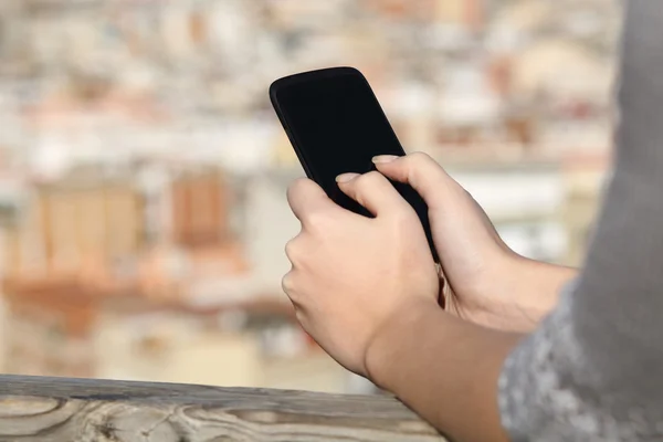 Donna mani sms su uno smartphone con sfondo urbano — Foto Stock