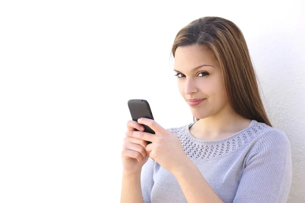 Mooie vrouw texting op een smartphone en camera te kijken — Stockfoto