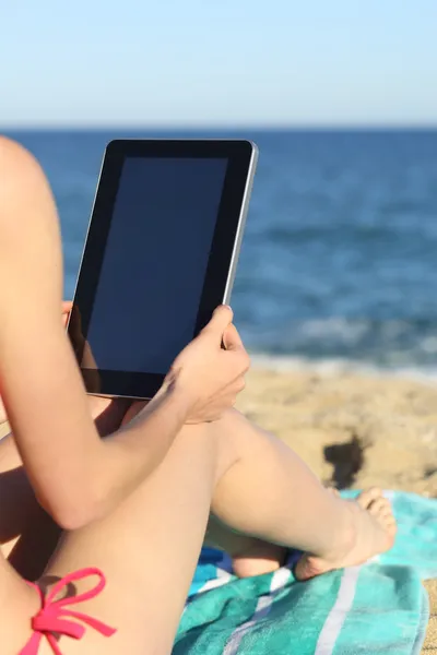 Женщина в отпуске читает планшет на пляже — стоковое фото