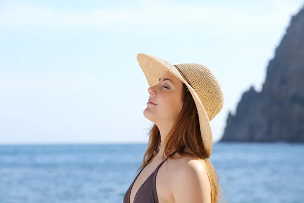 Счастливая женщина дышит свежим воздухом на пляже в шляпе — стоковое фото