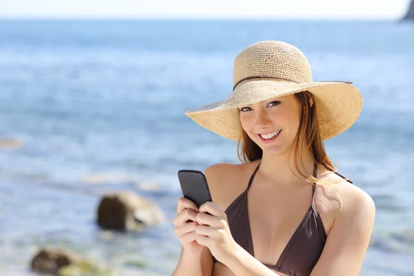 Bella donna felice sms su uno smartphone sulla spiaggia — Foto Stock