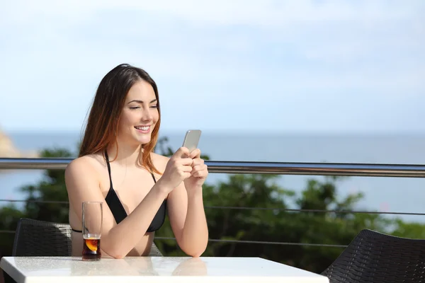 Glad kvinna med en smart telefon i en terrass på en restaurang — Stockfoto