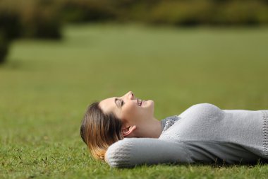 Beautiful woman resting on the grass in a park clipart