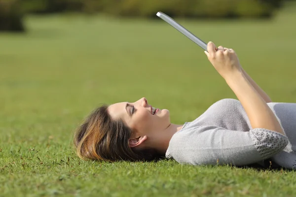 Profiel van:: een gelukkig vrouw leest een lezer van de Tablet PC op het gras — Stockfoto