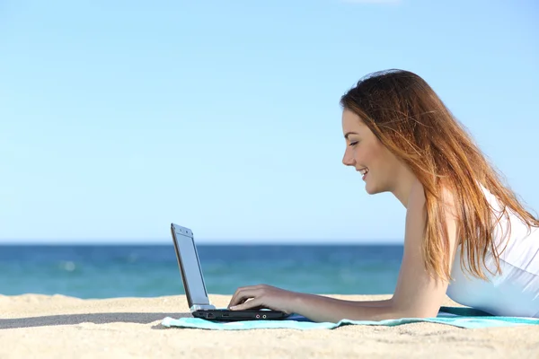 Seitenansicht eines Teenager-Mädchens, das am Strand mit einem Laptop surft — Stockfoto