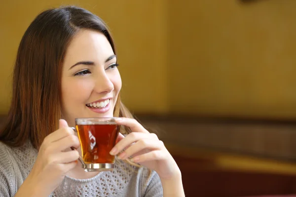 Ευτυχισμένη γυναίκα σκέφτεται κρατώντας ένα φλιτζάνι τσάι σε ένα καφενείο — Φωτογραφία Αρχείου
