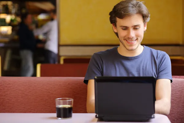 Homem feliz navegando na internet em um laptop em um restaurante — Fotografia de Stock