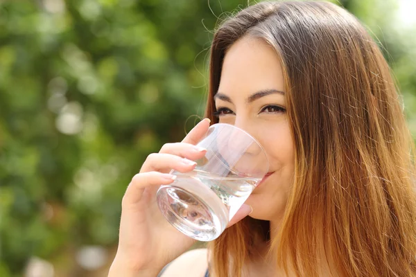 Mujer feliz bebiendo agua de un vaso al aire libre Imagen de archivo