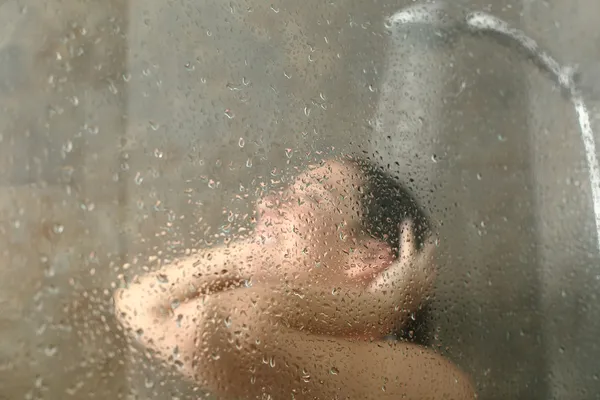 Портрет жінки, що приймає душ через екран ванни — стокове фото