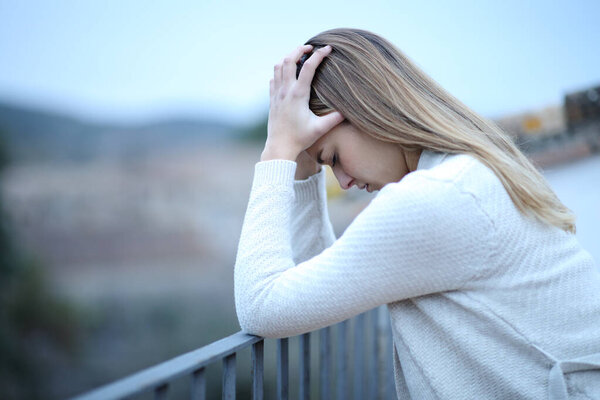Side view portrait of a depressed woman complaining in balcony