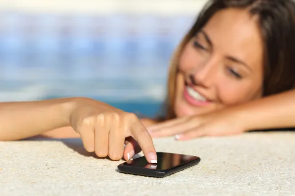 Mulher feliz em férias mensagens de texto em um telefone inteligente banho em uma piscina — Fotografia de Stock