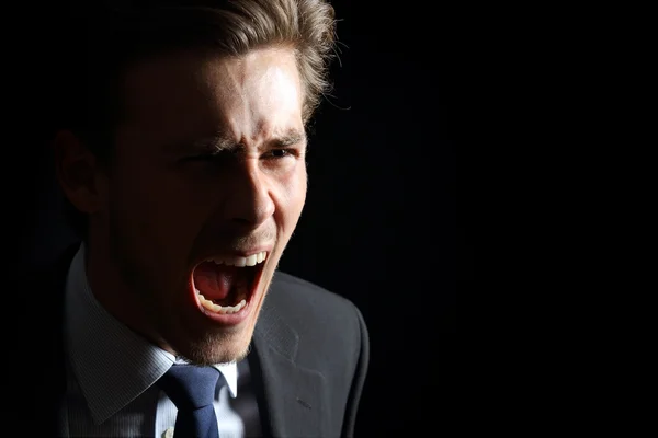 Angry businessman shouting isolated in black — Stock Photo, Image