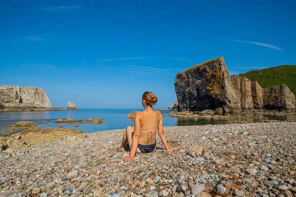 穿着比基尼的女人坐在美丽的孤零零的海滩上沉思暑假的风景 — 图库照片