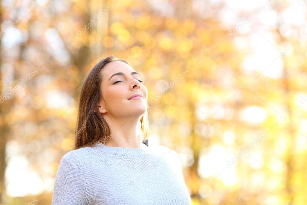Happy relaxed female breathing fresh air in autumn in a forest