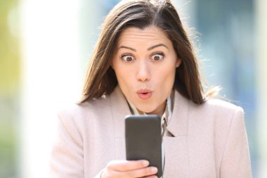 Şaşırmış bir yöneticinin ön görünüm portresi sokaktaki akıllı telefon içeriğini kontrol ediyor