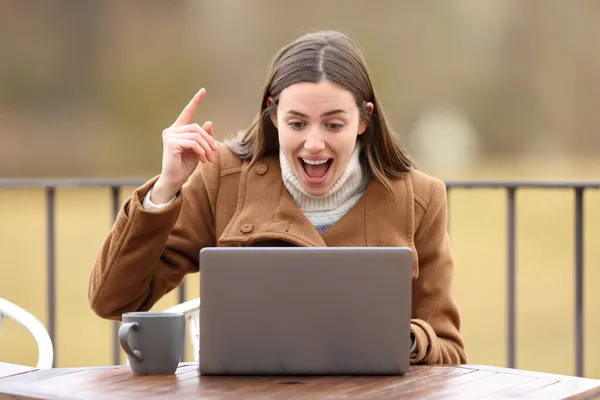 在冬天看到一个快乐的女人想在阳台上使用笔记本电脑 — 图库照片