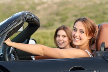 İki mutlu arkadaş dağda üstü açık bir arabada sana bakıyor.