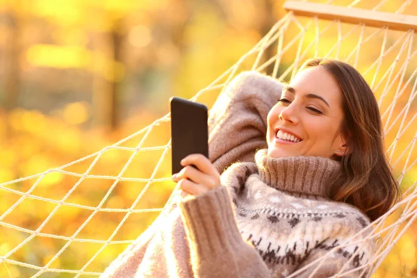 Mujer Feliz Relajarse Hamaca Cheking Teléfono Inteligente Atardecer Otoño —  Fotos de Stock