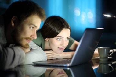 Gece evde dizüstü bilgisayardan medya içeriğini izleyen bir çift