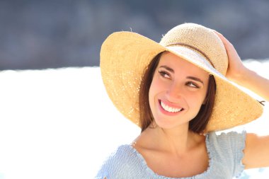 Pamela 'nın şapkasını sahilde tutarken mutlu bir kadın.