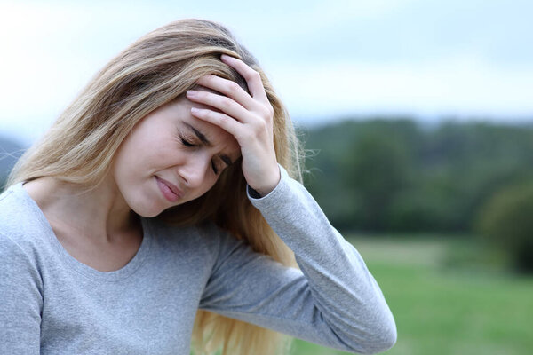 Teenage girl complaining suffering head ache in a field