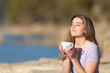 Rahatlamış gençler kahve içiyor ve doğada temiz hava soluyor.