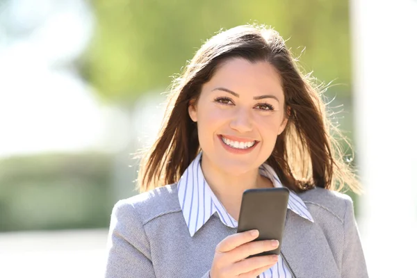 フロントビューポートレートの幸せなビジネス女性を見てカメラを保持スマートフォンで通り — ストック写真
