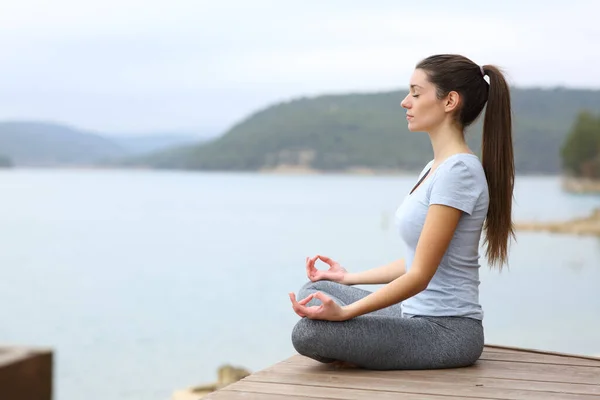 在阴天的湖中做瑜伽的女人的全身性特征 — 图库照片