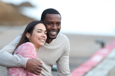 Irklar arası aşk flörtü yapan bir çift başka bir yere bakıyor ve bir iskelede sarılıyorlar.