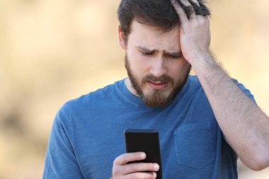 Dışarıdaki akıllı telefonları kontrol eden endişeli bir adamın portresi.