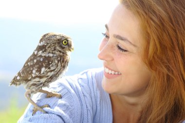 Baykuşlu güzel bir kadın doğada birbirine bakıyor.