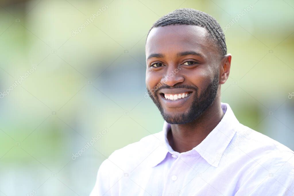 Handsome happy man with black skin and perfect smile looks at you in the street