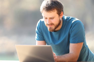 Doğada dizüstü bilgisayar kullanan tatmin olmuş bir adam.