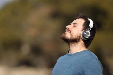 Doğada kablosuz kulaklıkla meditasyon yapan bir adamın profili