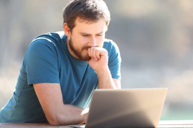 Dalgın adam doğada dizüstü bilgisayarın içeriğini kontrol ediyor.