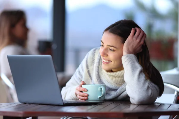 冬天快乐的女人在酒吧的阳台上观看笔记本电脑上的媒体 — 图库照片