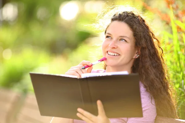 Szczęśliwa Kobieta Myśląca Patrząc Stronę Gotowa Napisania Notesie Parku — Zdjęcie stockowe