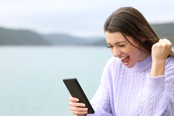 Excited Teen Celebrating Good News Lake Checking Smart Phone — стоковое фото