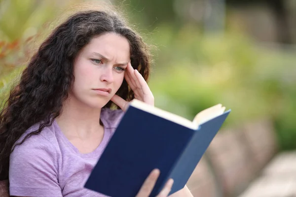 Збентежена Жінка Читає Погану Паперову Книгу Сидячи Парку — стокове фото
