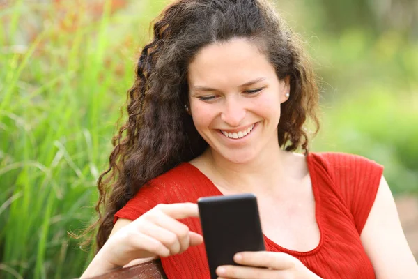 公園でスマートフォンを使用して赤の幸せな女性 — ストック写真