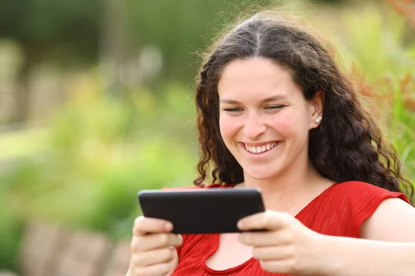 Parkta Mutlu Bir Kadın Parktaki Yatay Akıllı Telefondan Video Izliyor — Stok fotoğraf