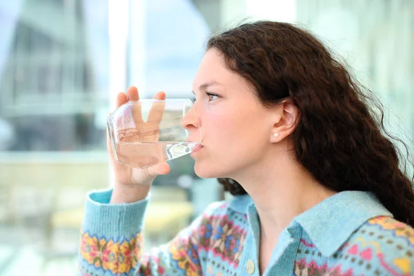 一个女人在吧台用玻璃杯喝水的侧景画像 — 图库照片