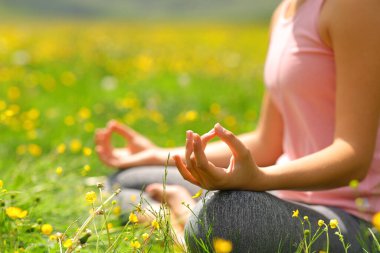 İlkbaharda yeşil bir tarlada yoga yapan bir yoginin portresini yakından çek.