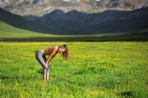 Side view portrait of an exhausted runner resting in a field in a high mountain