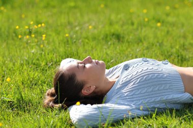 Woman resting and relaxing lying on the grass in the mountain