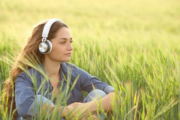 Mulher Pensativa Ouvindo Áudio Com Fones Ouvido Sem Fio Olhando — Fotografia de Stock