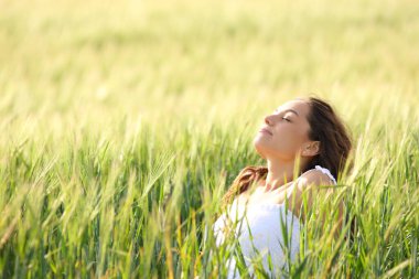 Relaxed woman sitting in a field breathing fresh air
