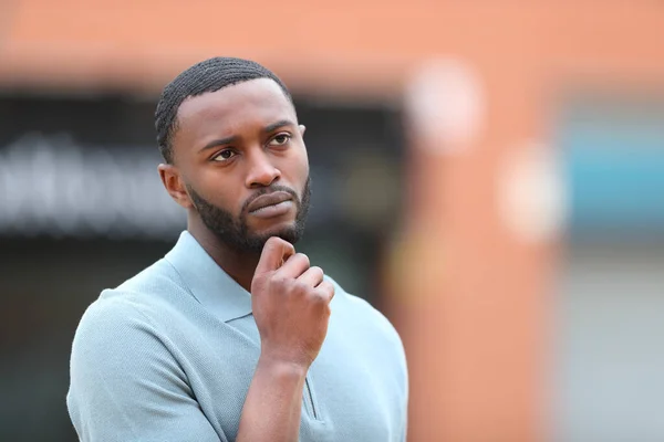 Serious black man thinking looking at side in the street