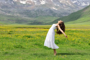 Beyaz elbiseli bir kadının dağda çığlık atarken yan görünümü.
